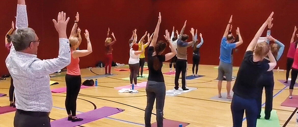 Teilnehmende beim Gesundheitstag der FH Kufstein Tirol während einer gemeinsamen Yoga-Übung in der Sporthalle.
