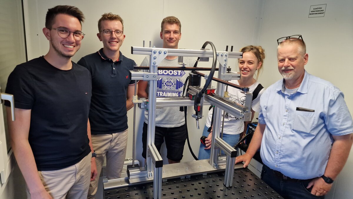 Ein Teil des Praxisprojektteams und die Auftraggeber präsentieren den fertigen Wire-Arc-Additive-Manufacturing-Desktop-Drucker.