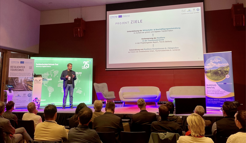 Mario Situm präsentiert das Interreg-Projekt Resilienter Tourismus auf der Bühne im Festsaal
