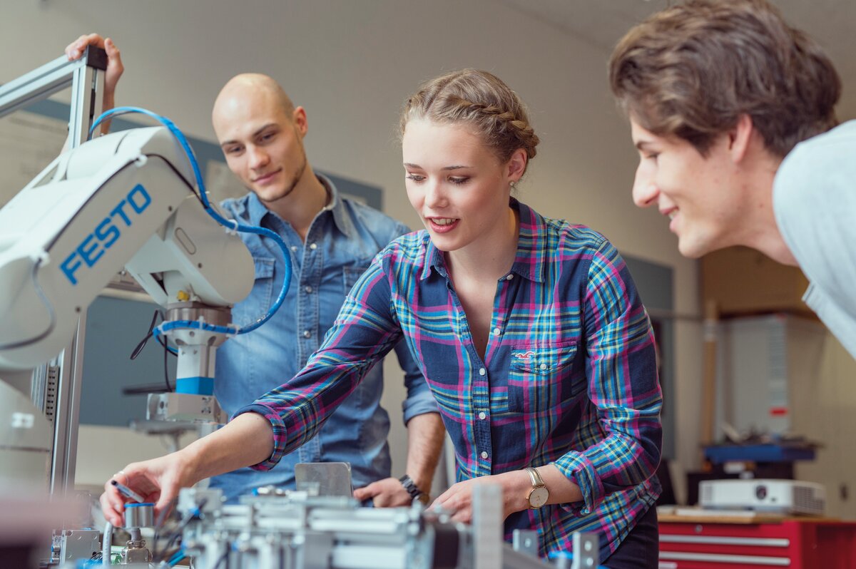 Studierende arbeiten gemeinsam an einer technischen Versuchsanlage mit Festo-Roboterarm im Labor der FH Kufstein Tirol.
