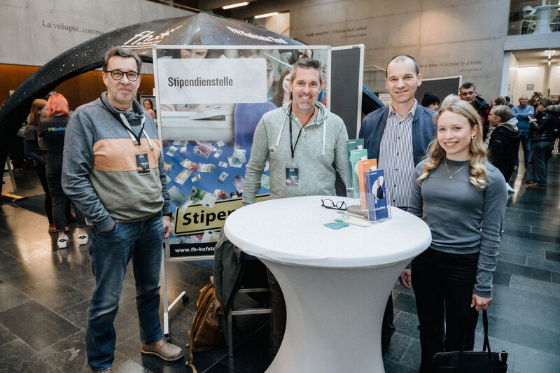 Personen posieren am Stand der Stipendienstelle am Tag der offenen Tür an der FH Kufstein Tirol. 