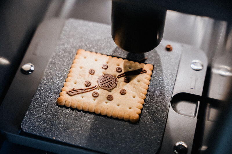 Im Makers Lab der FH Kufstein Tirol wird das Logo der FH mit Schokolade auf einen Keks gedruckt.