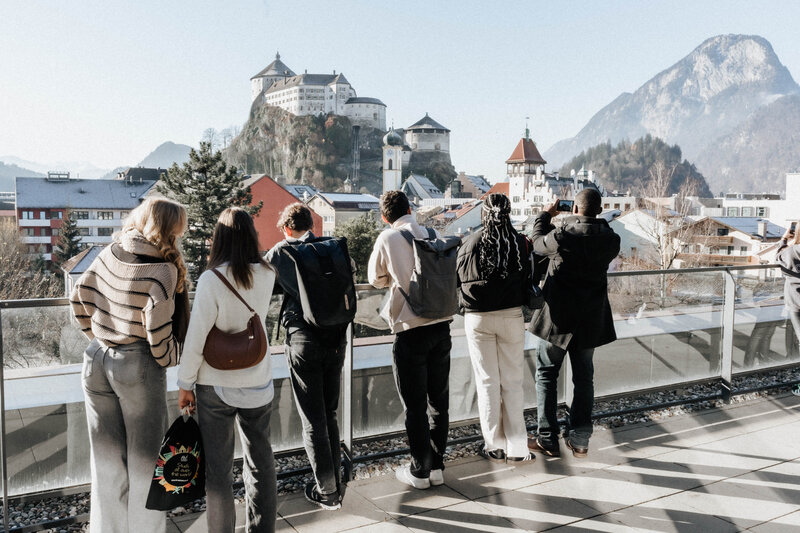 Mehrere Gäste am Tag der offenen Tür an der FH Kufstein Tirol blicken von der Dachterrasse auf die Festung. 