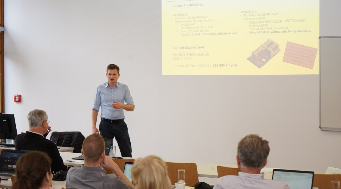 Alexander Schiegl hält einen Vortrag beim Workshop über den Einsatz von KI-Agenten im Marketing an der FH Kufstein Tirol. Die Präsentation im Hintergrund zeigt Berechnungen zu Grafikkartenkosten.