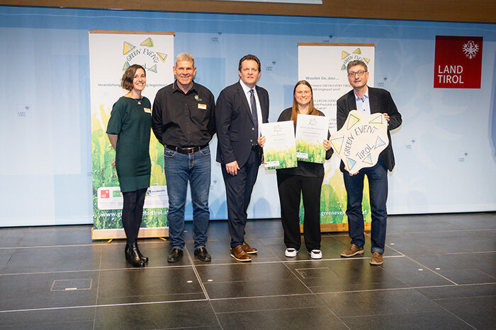 Personen stehen auf der Bühne mit der Urkunde