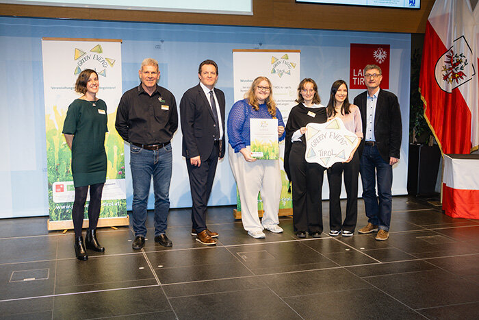 Personen stehen auf der Bühne wegen der Urkundenübergabe