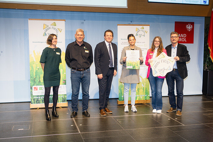 Personen stehen zur Übergabe der Urkunden auf der Bühne