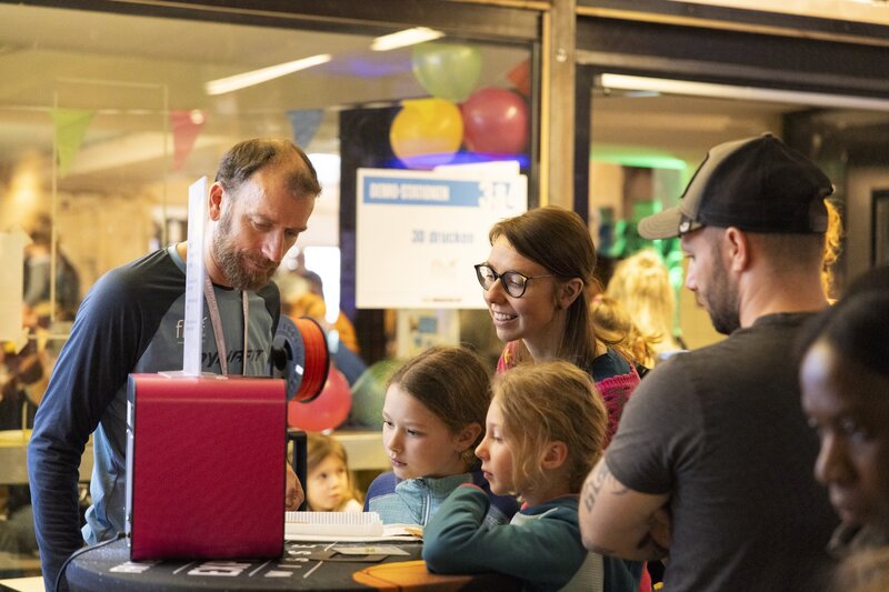 Markus Ehrlenbach mit Kindern und Eltern am 3D-Drucker