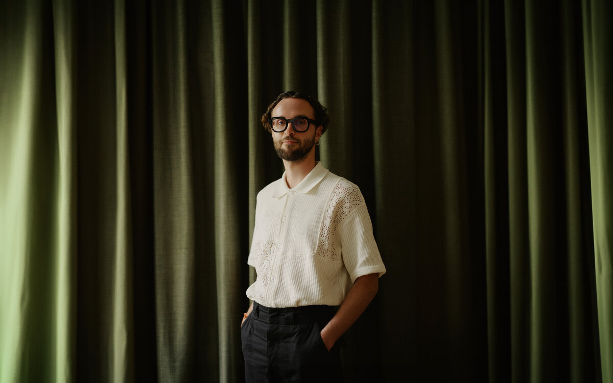 M. Mauracher steht vor einem grünen Vorhang