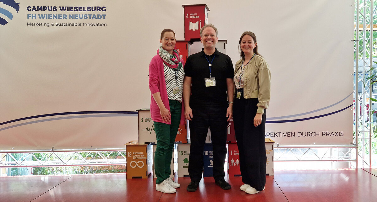 Drei Personen stehen nebeneinander auf der Bühne. 