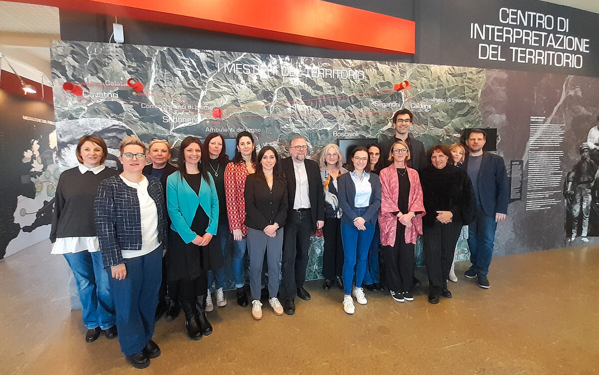 Partner:innen im Museum mit einer Landkarte der Alpen