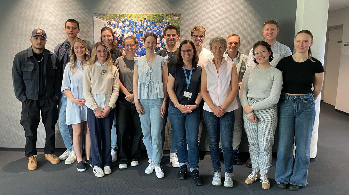 Exkursion Freudenberg Teilnehmende der Exkursion in zwei Reihen nebeneinander vor einer grauen Wand mit einem Bild