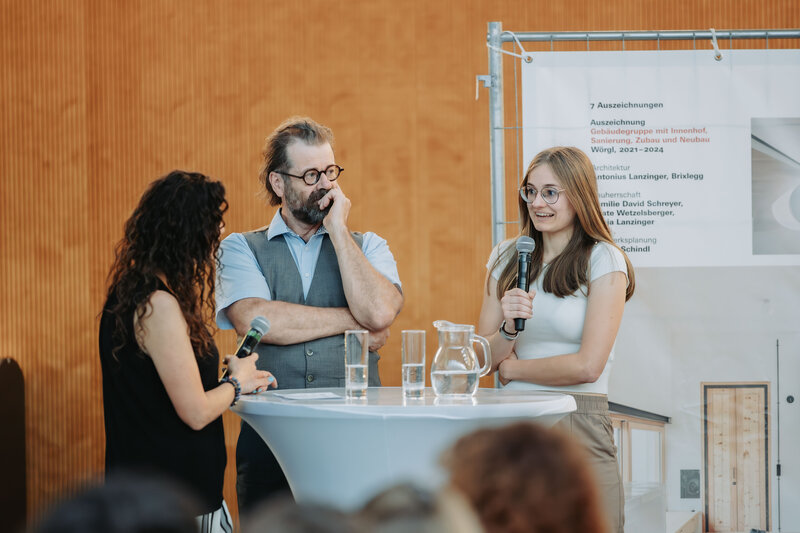Eine Gruppe steht vor einer Holzwand mit einem Mikrofon.