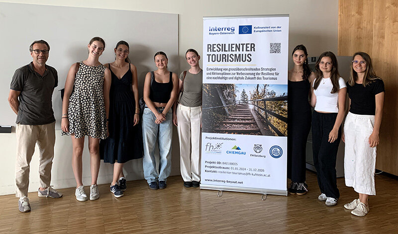 Schülerinnen mit Lehrer und einem Roll-up des Resilienten Tourismus