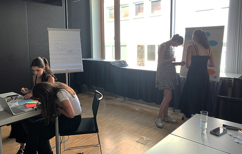 Schülerrinnen arbeiten am Tisch und am Flipchart