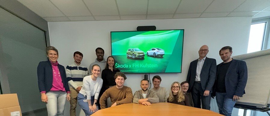 Praxisprojekt Skoda Personen stehen im Büro für ein Gruppenbild zusammen