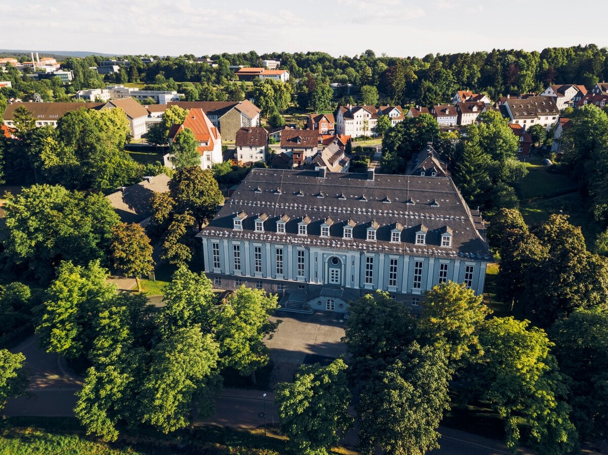 Drohnenaufnahme der Aula der TU Clausthal, umgeben von Bäumen und angrenzenden Gebäuden.