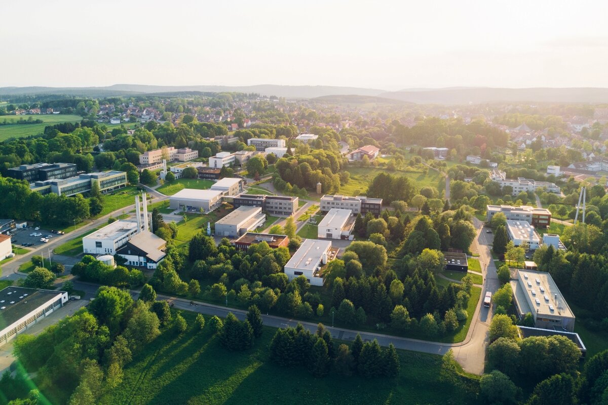 Drohnenaufnahme des Campus der TU Clausthal mit mehreren Institutsgebäuden, umgeben von viel Grün und Bäumen.