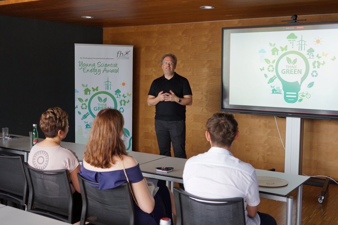 Sprecher beim Young Scientist Energy Award vor Teilnehmenden mit Präsentation zum Thema Nachhaltigkeit.