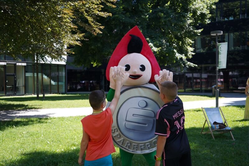 Zwei Kinder schlagen mit dem Sparkassen-Maskottchen ein.