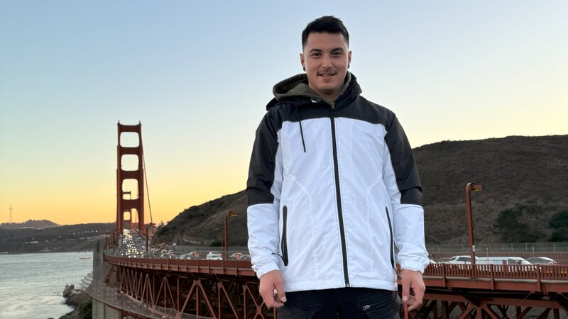 Student steht vor der Golden Gate Bridge in San Francisco bei Sonnenuntergang