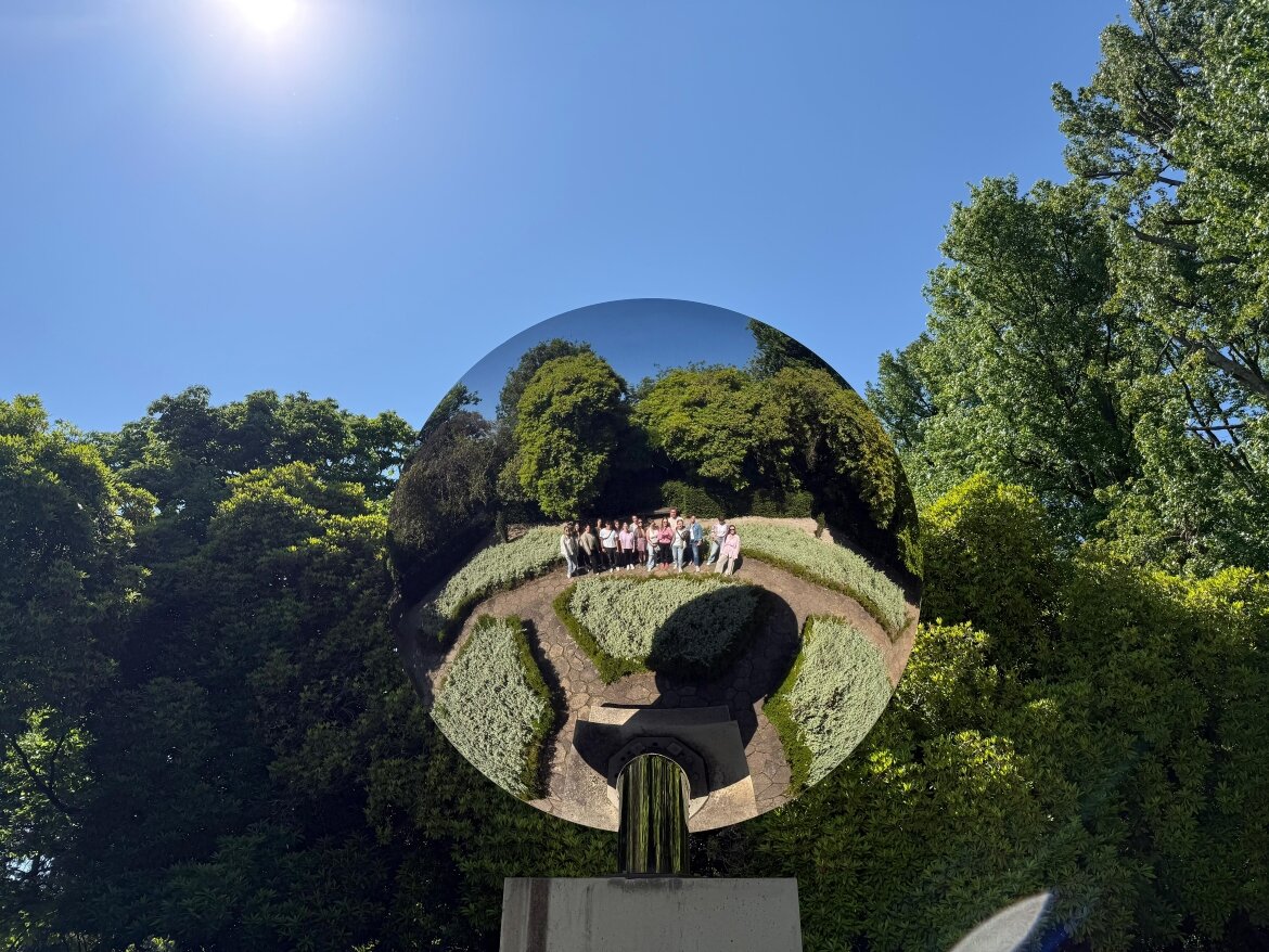 Studienreise SKVM | Studierende im Park Serralves in Porto Spiegelnde Kugel im Park Serralves in Porto, in der eine Gruppe von Studierenden der FH Kufstein Tirol reflektiert wird