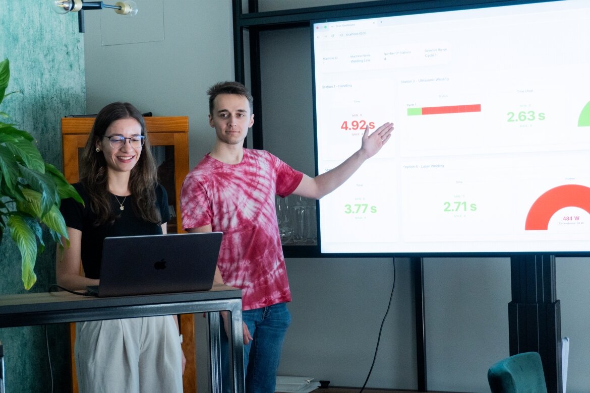 Zwei Studierende aus dem Praxisprojekt der FH Kufstein Tirol bei ihrer Abschlusspräsentation im Hause der Firma 3CON mit den visualisierten Sensordaten, abgebildet auf einem Bildschirm. 