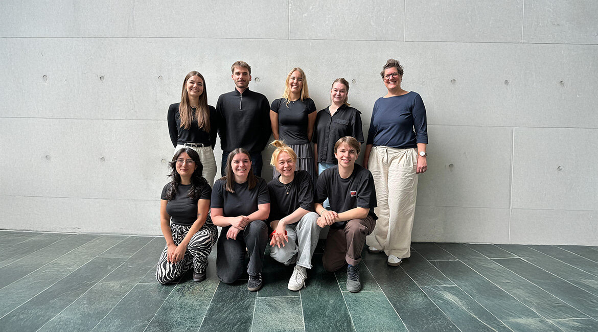 Gruppenfoto von acht Studierenden und einer Professorin der FH Kufstein Tirol vor einer Betonwand, die gemeinsam das Kurzfilmfestival organisieren.