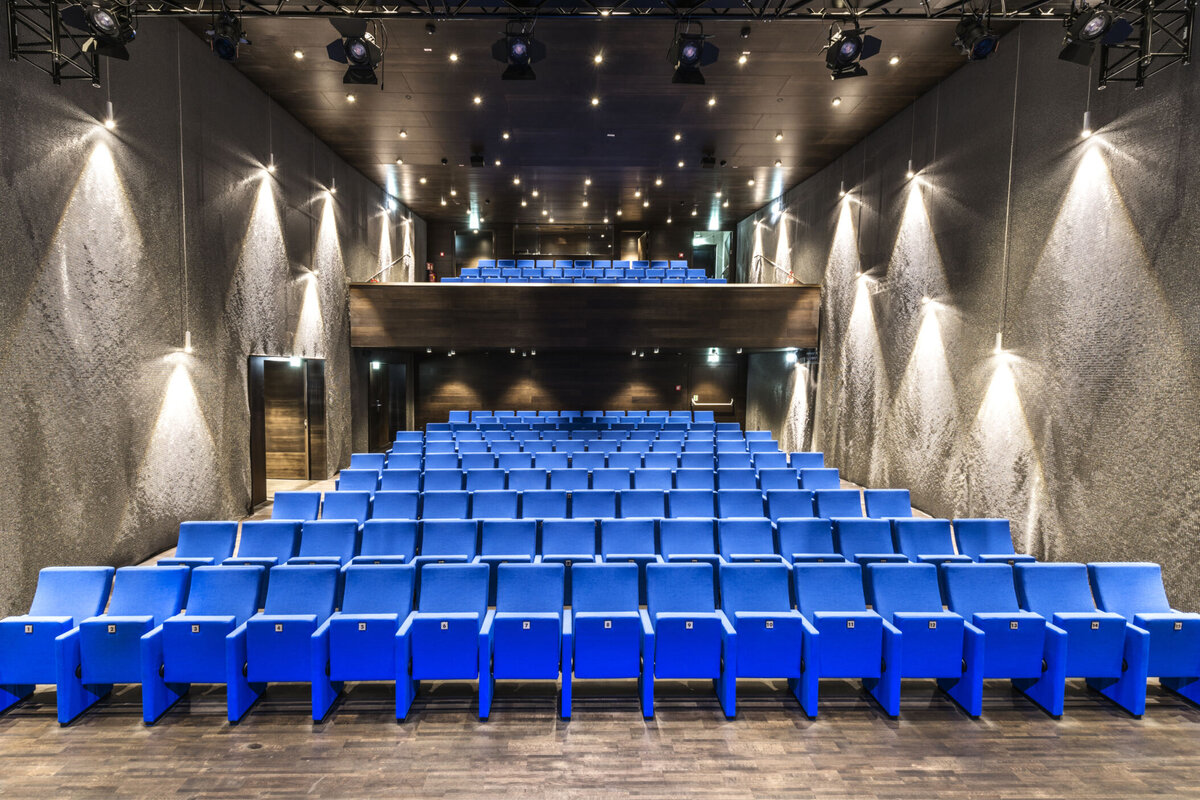 Blick in den modernen Kinosaal des Kultur Quartier Kufstein mit blauen Sitzreihen und Galerie, vorbereitet für das Kurzfilmfestival des Studiengangs SKVM.