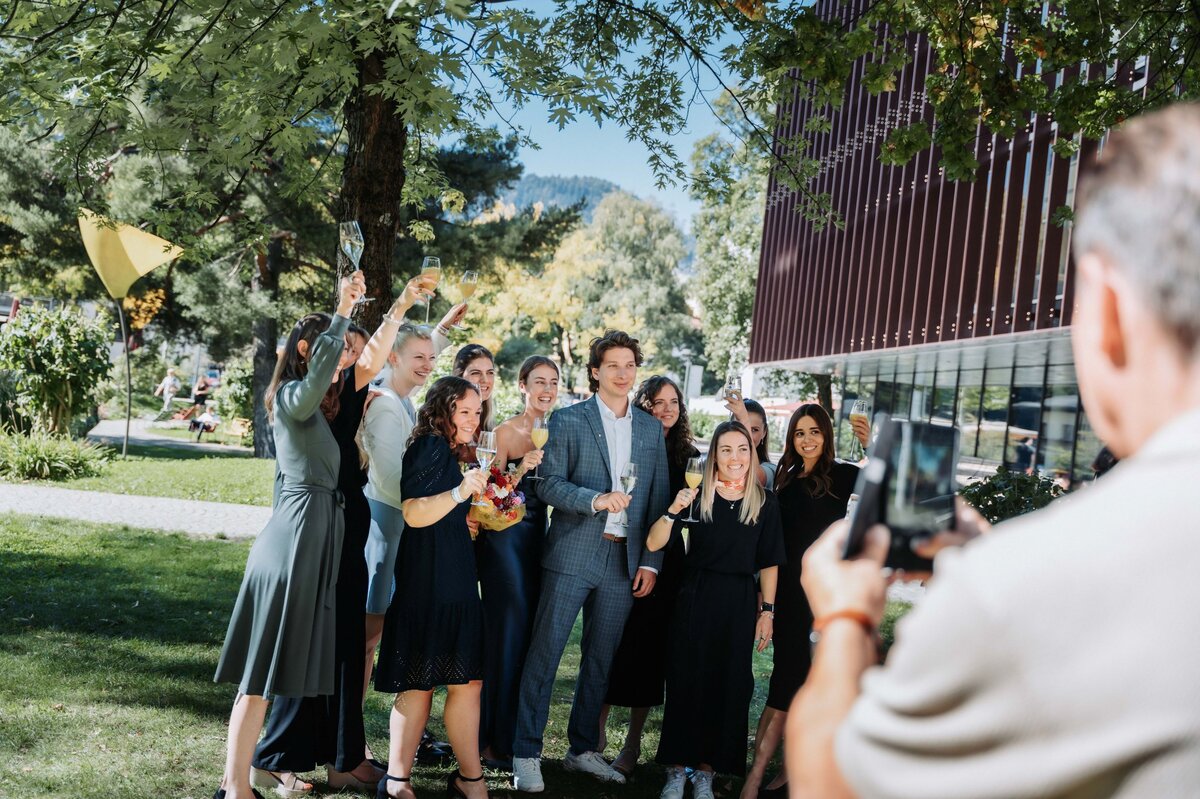 Sponsion 2025: Spondierende stoßen gemeinsam an. Spondierende der FH Kufstein Tirol stoßen im Außenbereich der Hochschule gemeinsam an.