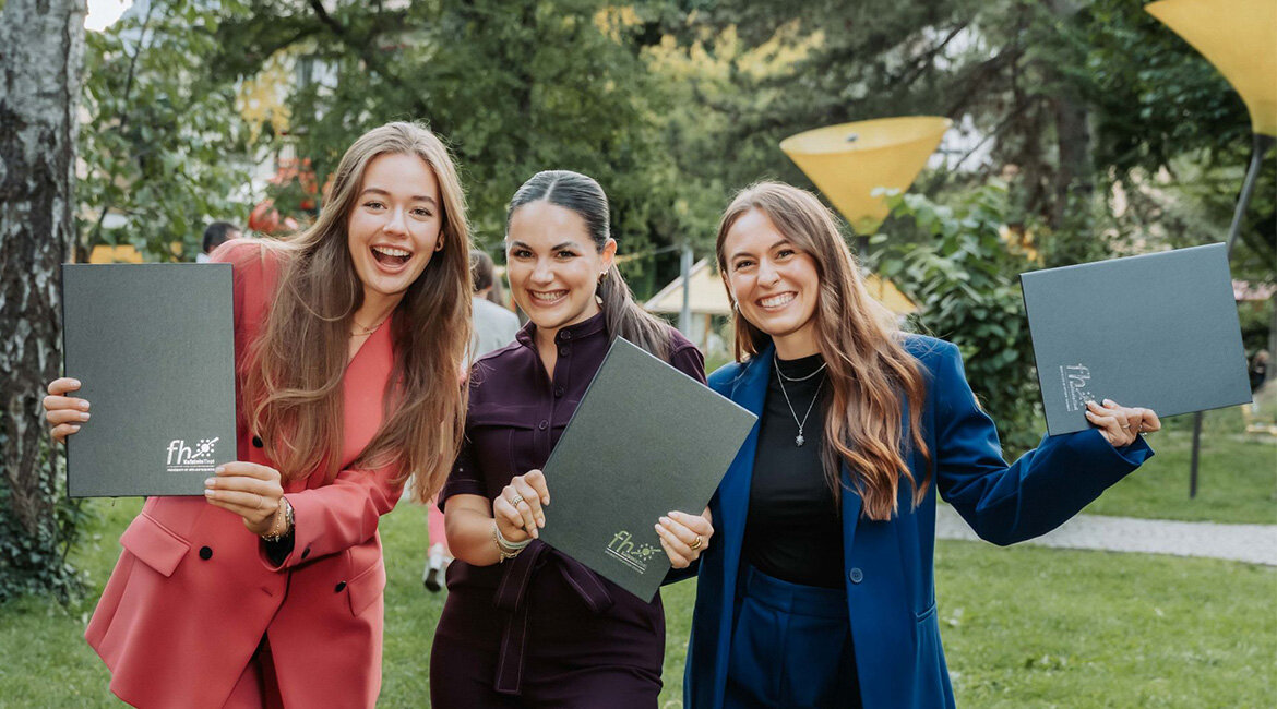 Sponsion 2025 an der FH Kufstein Tirol: Absolventinnen auf dem Campus Drei fröhliche Absolventinnen lächeln auf dem Campus der FH Kufstein Tirol für die Kamera.