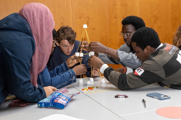 Eine diverse Gruppe Studierender baut gemeinsam eine Struktur aus Spaghetti und Marshmallows im Rahmen eines Workshops zu Teamarbeit und Problemlösung. | © FH Kufstein Tirol