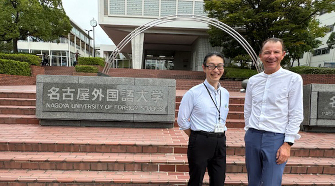 Eingang Partnerhochschule Nagoya University of Foreign Studies FH-Geschäftsführer Prof. (FH) Dr. Thomas Madritsch und Masamine Tamai vor einer roten Steinstiege der japanischen Partnerhochschule Nagoya University.