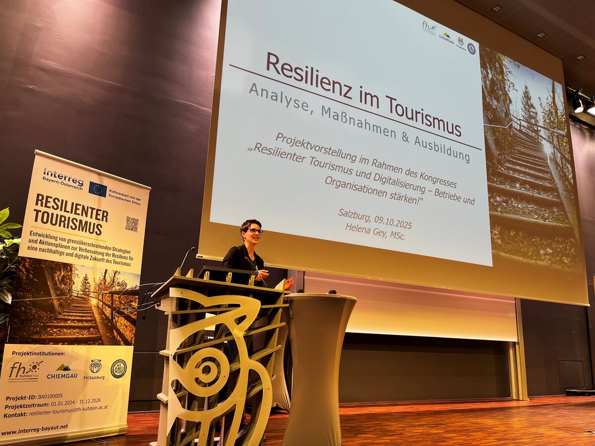 Frau steht am Rednerpult auf der Bühne.