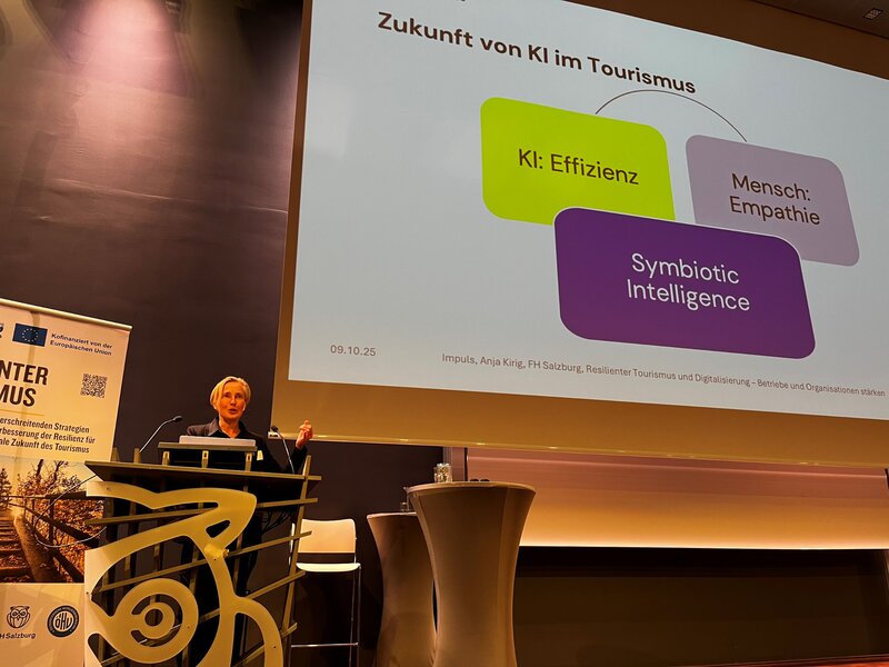 Frau steht am Redepult und spricht in das Mikrofon.