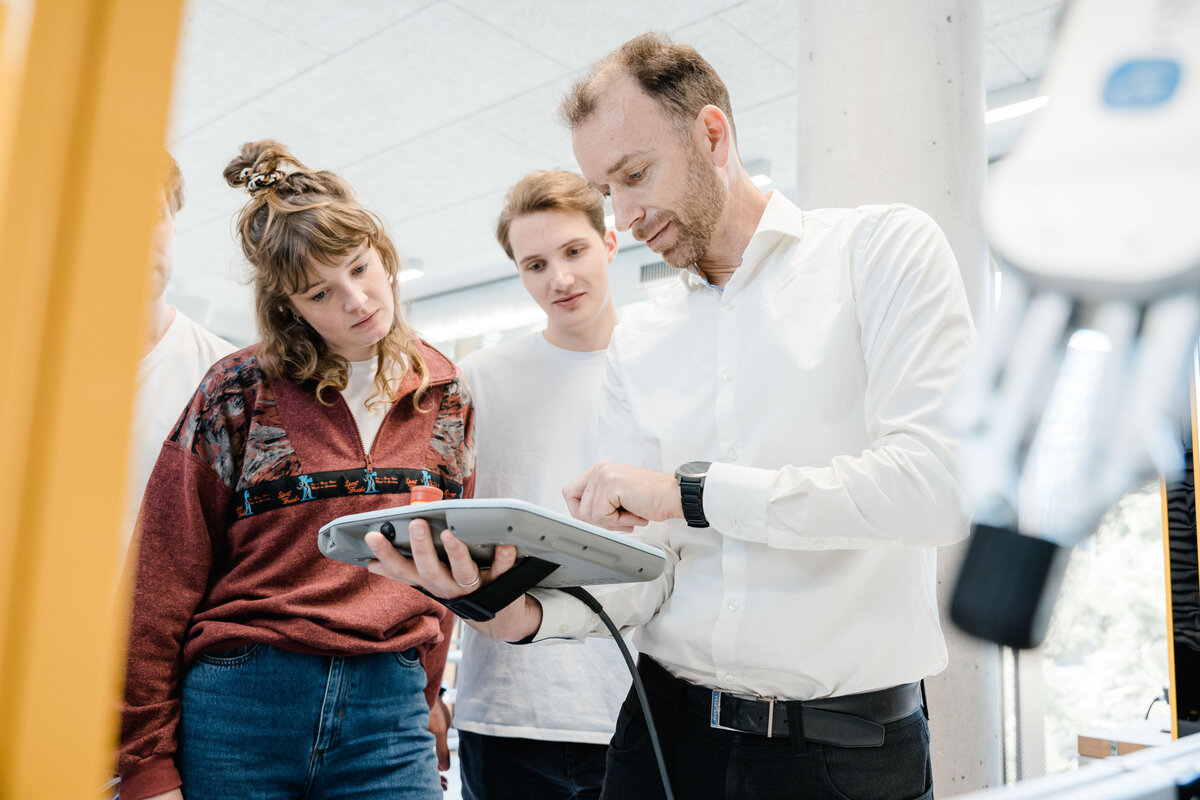 Markus Ehrlenbacher erklärt Studierenden ein Steuergerät im Automation Lab der FH Kufstein. Die Gruppe verfolgt interessiert die Demonstration.