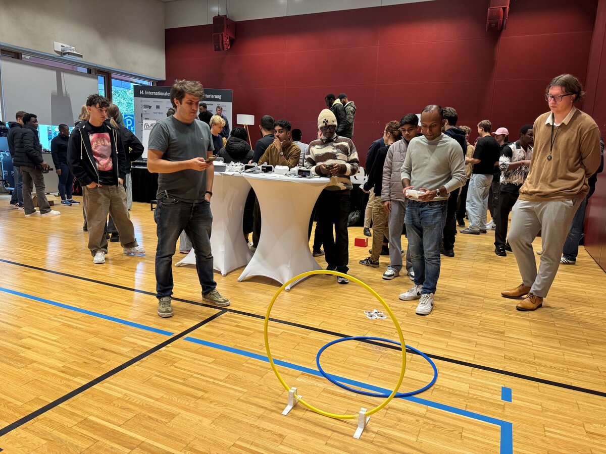 Personen stehen um einen Flugparcour für Drohnen.