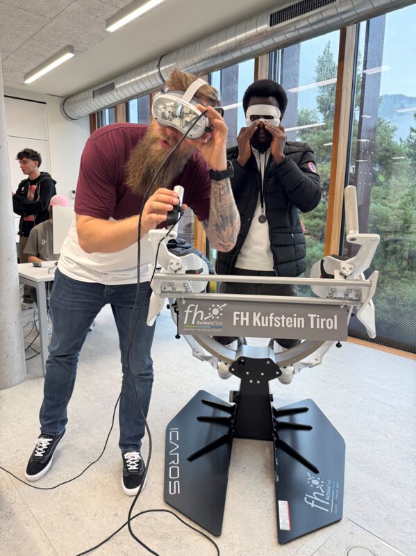 Zwei Personen stehen vor dem Icaros-Simulator.