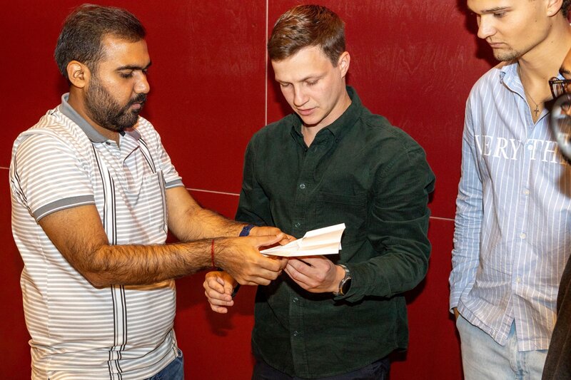 Ein Mann präsentiert ein Stück Papier, während er aufmerksam darauf blickt.