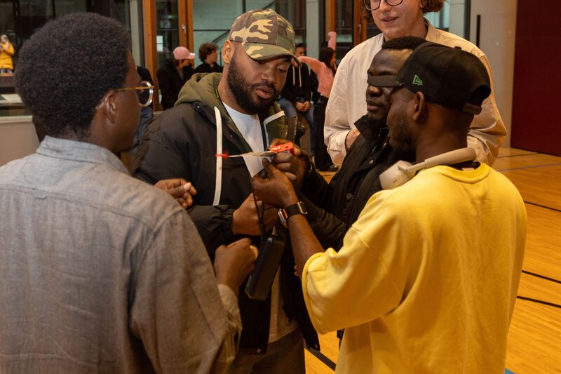 Personen stehen zusammen und einer hält einen Papierflieger in die Mitte.