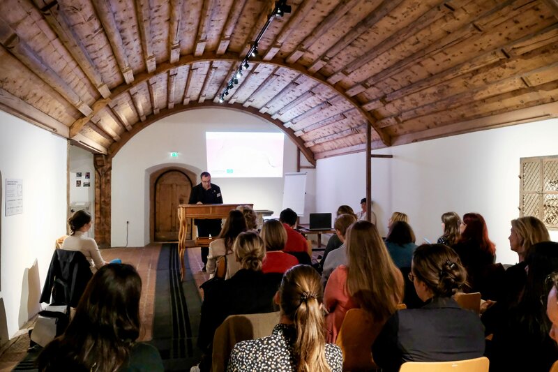 Personen sitzen vor einem Rednerpult.