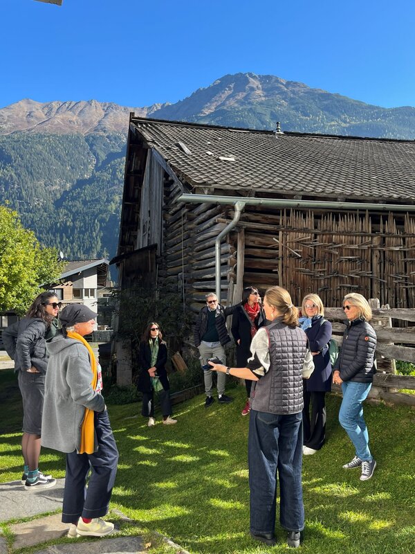Personen stehen vor einer Scheune bei Sonnenschein