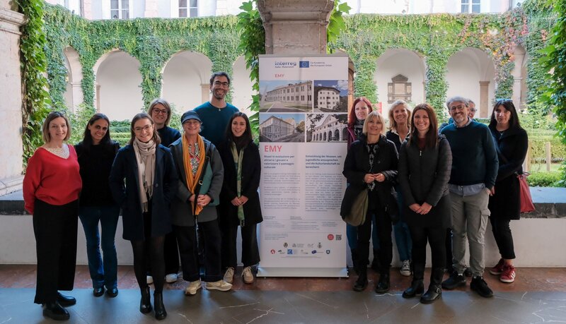 Eine Gruppe von Personen posiert vor einem großen Plakat für ein Foto.