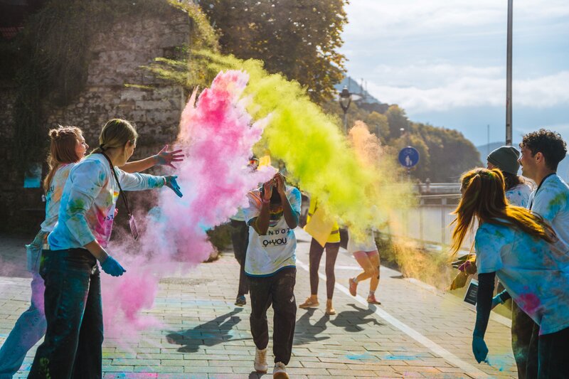 Personen stehen um eine andere Person und bewerfen diese mit Farbe.