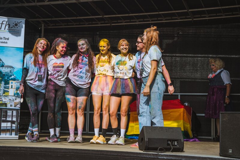 Personen stehen auf der Bühne und sind sichtlich mit der Farbe getroffen worden.
