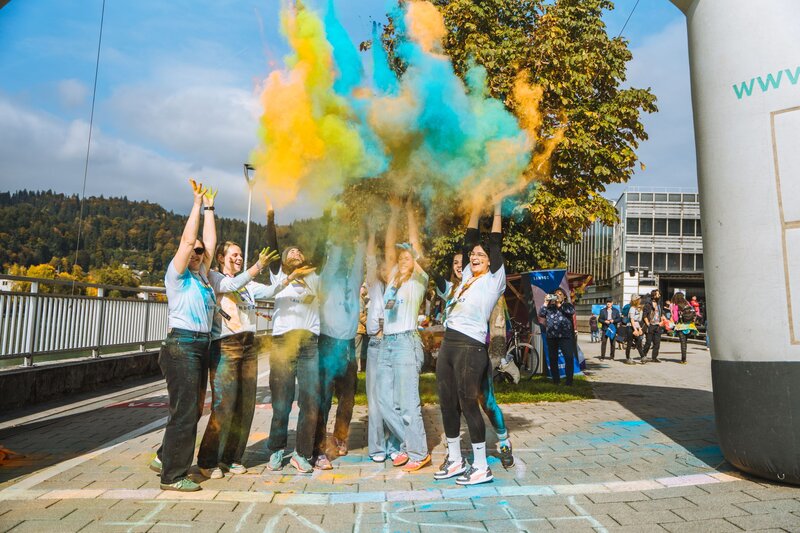 Gruppe wirft Farbe in die Luft.