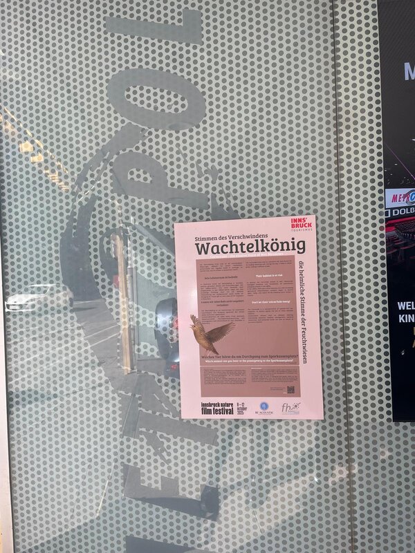 Ein rotes Plakat an einer Glaswand.