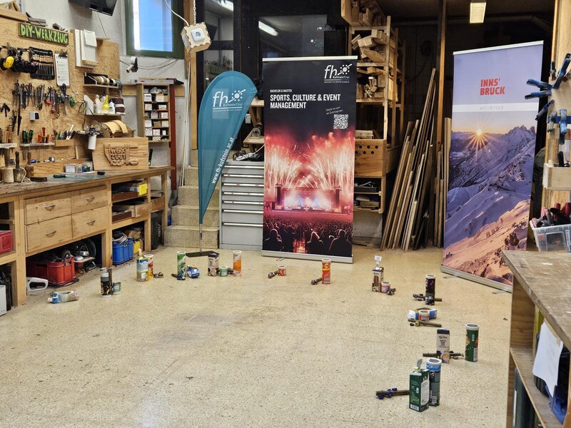 Ein Roll-up der FH Kufstein steht in einem Werkraum.