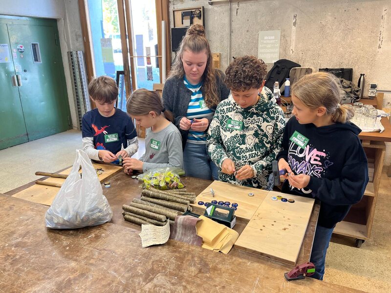 Kinder stehen um einen Werktisch.