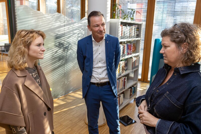 Drei Personen stehen sich im Kreis gegenüber.